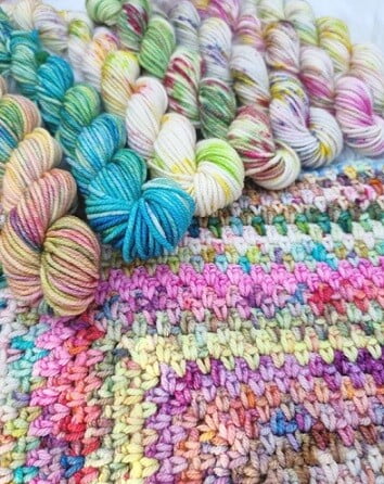 brightly coloured skeins of yarn on a crocheted blanket