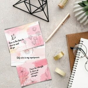 Positive affirmations cards for women on a desk with a pen, washi tape, notebook and glasses