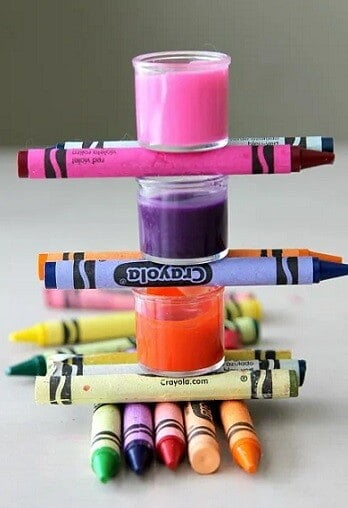3 pots of homemade lip gloss balanced on crayons
