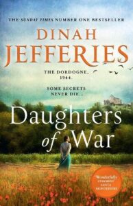 Book cover for Daughters of War by Dinah Jefferies. Country scene with a young white woman with her back to the reader, shoulders back and hands behind her back facing trees, mountains and a house on a hill with a field of poppies behind her