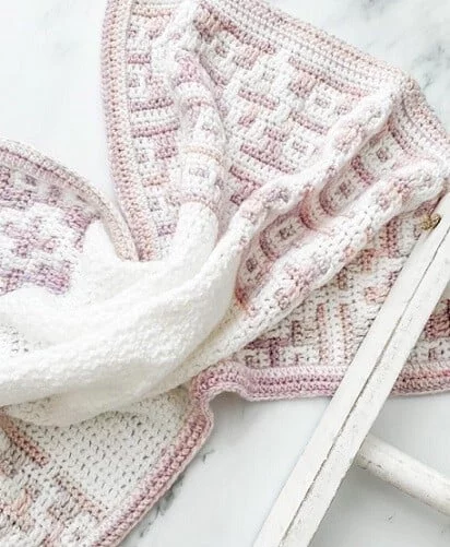 Mosaic crochet baby blanket in gold and white on a white background