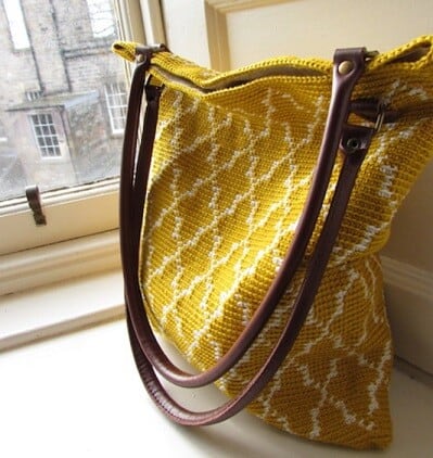 Moroccan crocheted tote bag in gold and white on a ledge in front of a window