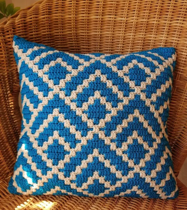A cushion in blue and white made from overlay mosaic crochet