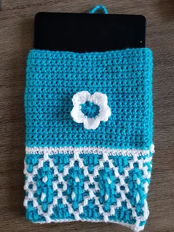 crochet tablet cover in turquoise and white with the device showing at the top of the tablet cozy