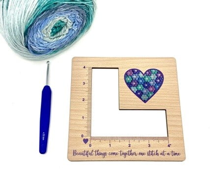 wooden tension gauge tool, blue yarn and a blue crochet hook