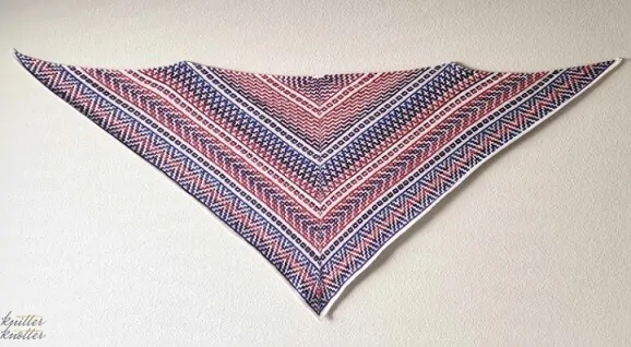 A colourful mosaic shawl is stretched out full length on a wall