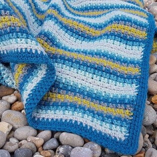 crochet blanket in blue, grey and a pop of colour with lime