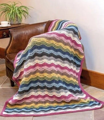 crochet blanket in ripple stitch in blues, greens, pinks