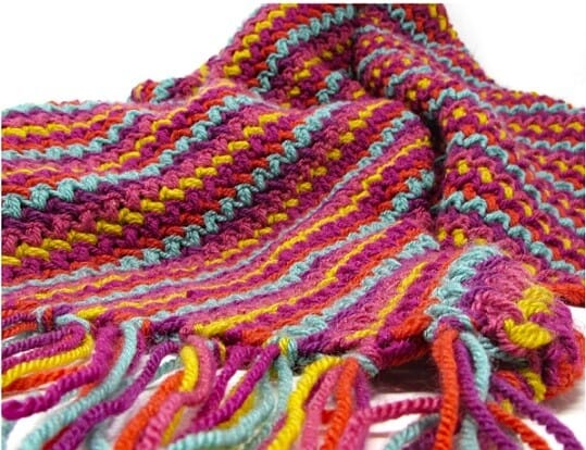 Colourful crochet blanket in deep pinks, mauve, yellow, green and red