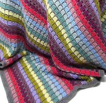 blanket crocheted in different shades of blue, cream, green, pink and red