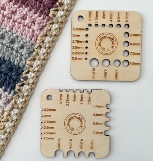 Two wooden hook gauge tools are laid flat next to a crocheted blanket
