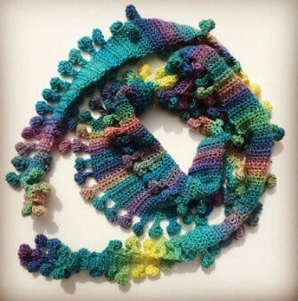 novelty crocheted scarf multicoloured with pompoms crocheted into the scarf
