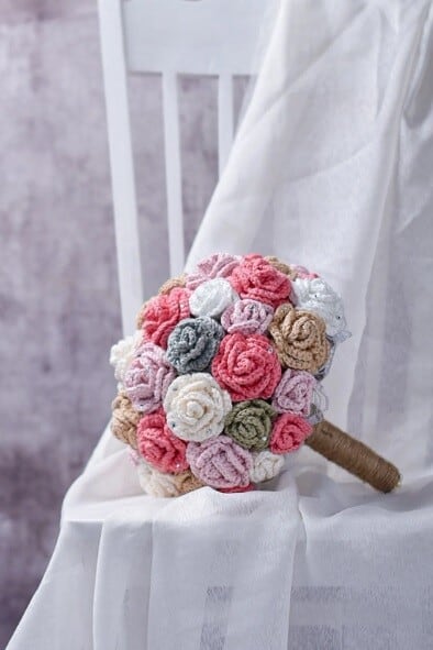 A wedding bouquet is crocheted in different colours resting on a chair