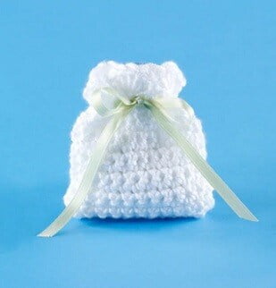 small crocheted pouch in white with silk ribbon and a blue background
