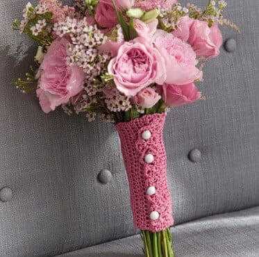 Bouquet of pink flowers with a lacy pink crocheted wrap around the stems