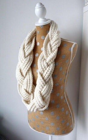 A cream scarf is styled on a mannequin