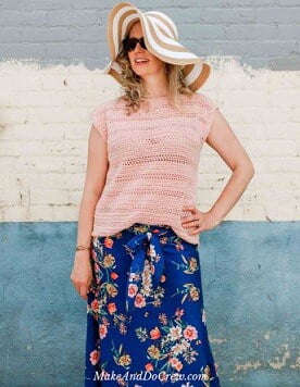 women standing with her left arm on her hip wearing a sun hat, crochet top and floral skirt