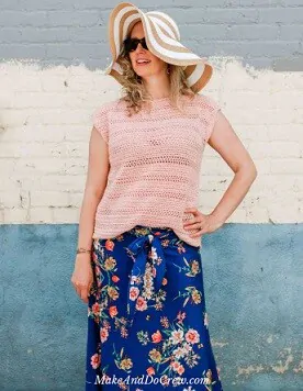 women standing with her left arm on her hip wearing a sun hat, crochet top and floral skirt