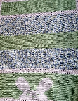 crochet baby blanket with a bunny peeking over the bottom of the blanket