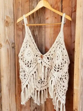 Crochet top made from granny squares in beige yarn hanging on a coat hanger