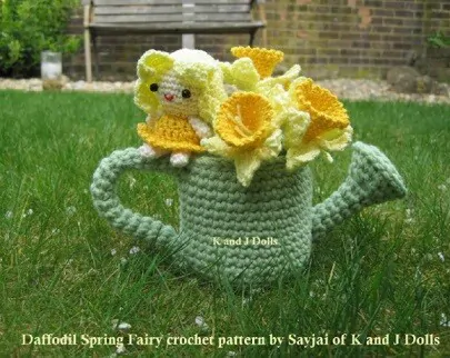 green crocheted watering can with crochet daffodils and a fairy