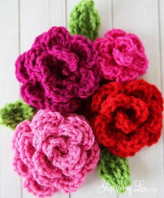 4 roses crocheted in different sizes in different shades of pink and red