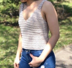 woman from the shoulders down wearing a crochet tank top and jeans