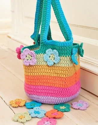 market bag crocheted in stripes of pink, lilac, orange, yellow, cream and turquoise with flowers around the top