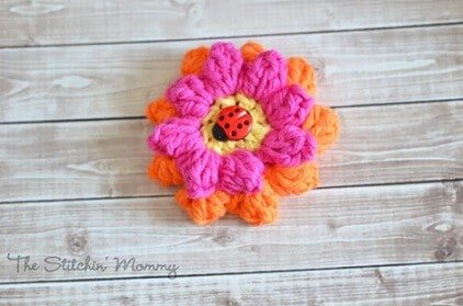 popcorn crochet flower in pink and orange with a ladybird in the middle