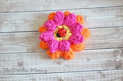 popcorn crochet flower in pink and orange with a ladybird in the middle