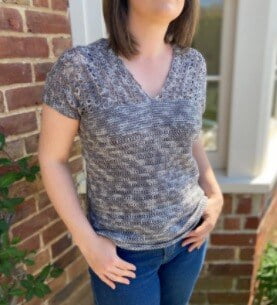 Woman from her shoulders down wearing a crochet top and jeans