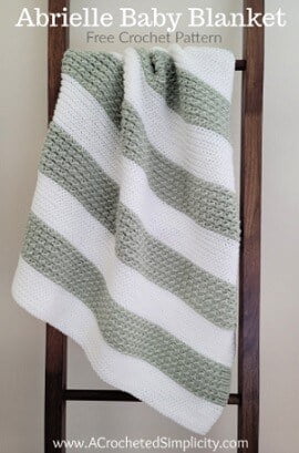 baby blanket to crochet in stripes of white and beige draped from a ladder