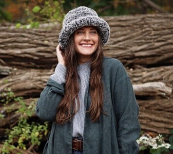 A women dressed for winter in a scarf and coat is also wearing a faux fur hat
