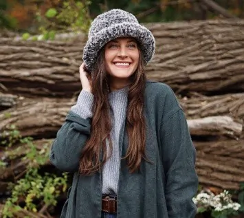 A women dressed for winter in a scarf and coat is also wearing a faux fur hat