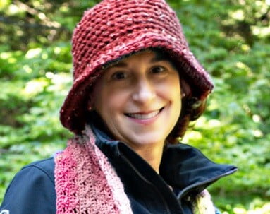 A woman is wearing a coat, scarf and hat
