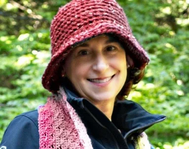 A woman is wearing a coat, scarf and hat
