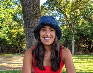 A woman is wearing a red tshirt and a blue sun hat
