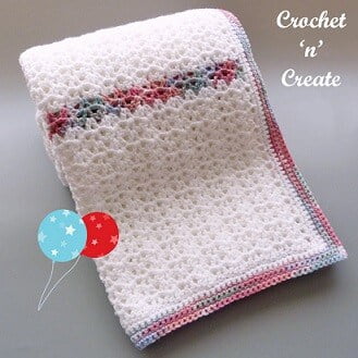 baby blanket crocheted in white with stripes of variegated colour