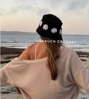the back view of a woman wearing a daisy sun hat and pink cardigan