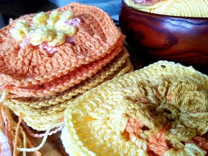 flower granny squares in different colours stacked on a table