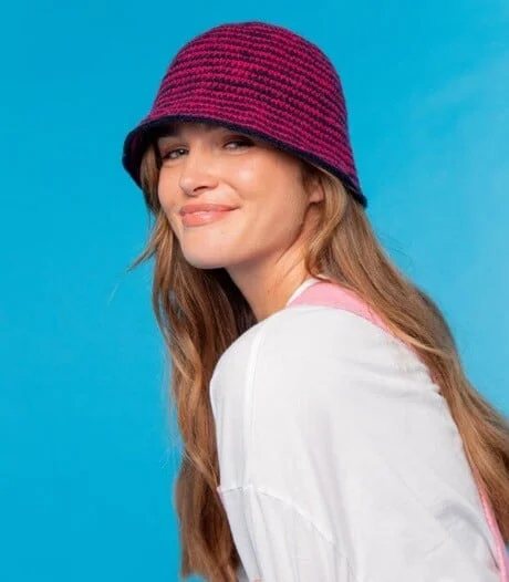 a woman is wearing a bucket hat crochet and smiling