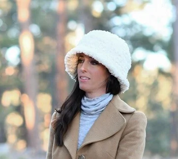 A woman is dressed for winter in a roll neck jumper, coat and faux fur hat