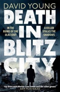 Book cover for Death in Blitz City by David Young. The silhouette of a man stands in bombed ruins