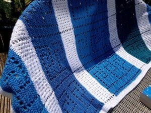 crochet blanket with a pattern of Greek Key in hues of blue and panels of white