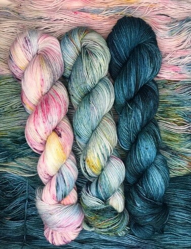 3 skeins of hand dyed yarn in deep blue, light blue and yellow, pink and light blue