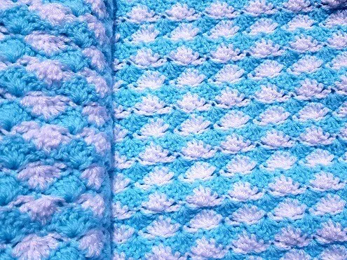 A close up of the fan shaped shell stitches used in a crochet blanket