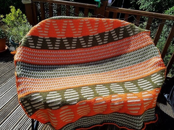 crocheted blanket in mosaic and Alpine stitch using colours green, orange, grey and oatmeal