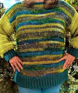 woman standing with her hands on hips to show the design of a crochet sweater