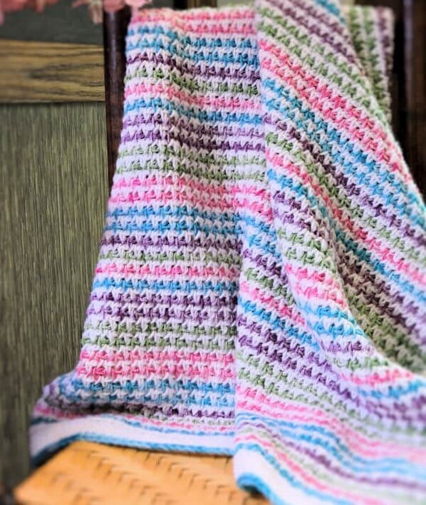 baby blanket created from Tunisian crochet is draped over a chair