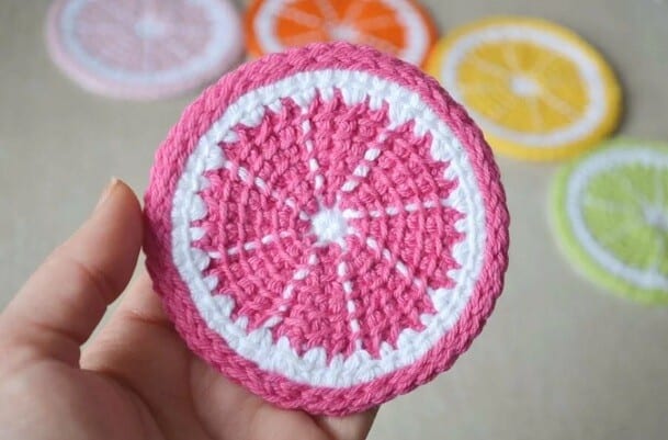 a hand is holding up a coaster crocheted in Tunisian Simple Stitch